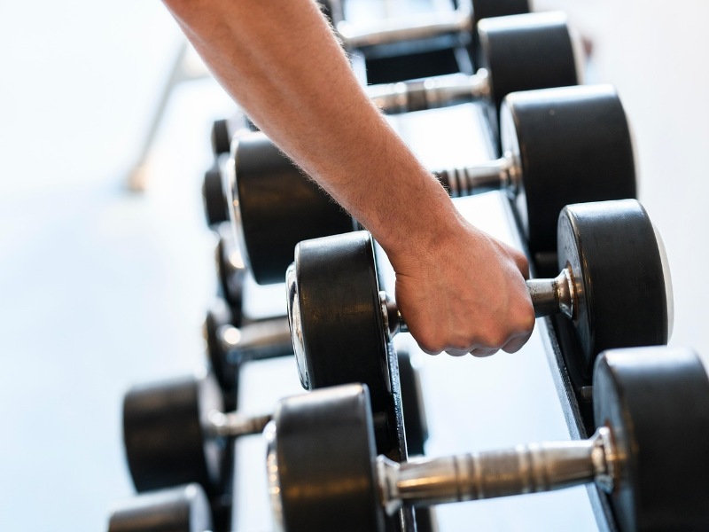 Person lifting dumbbell weights during a strength training workout.