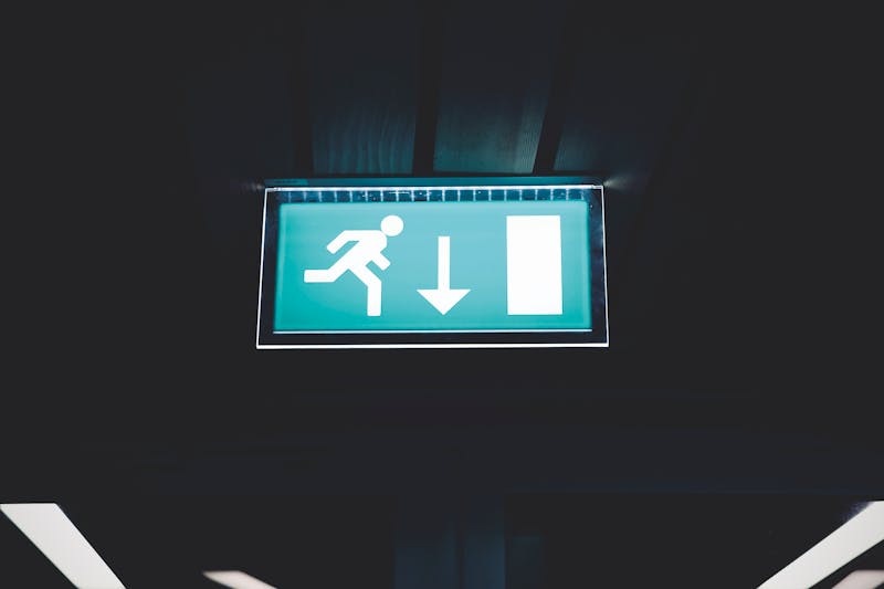 Illuminated green fire exit sign mounted on an indoor wall.
