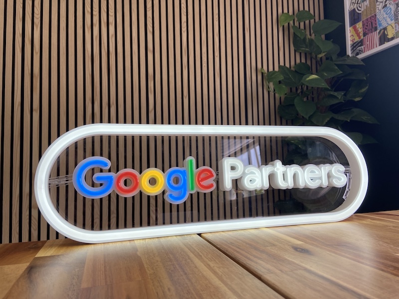 Illuminated Google Partner sign on the wall of a modern green meeting room.