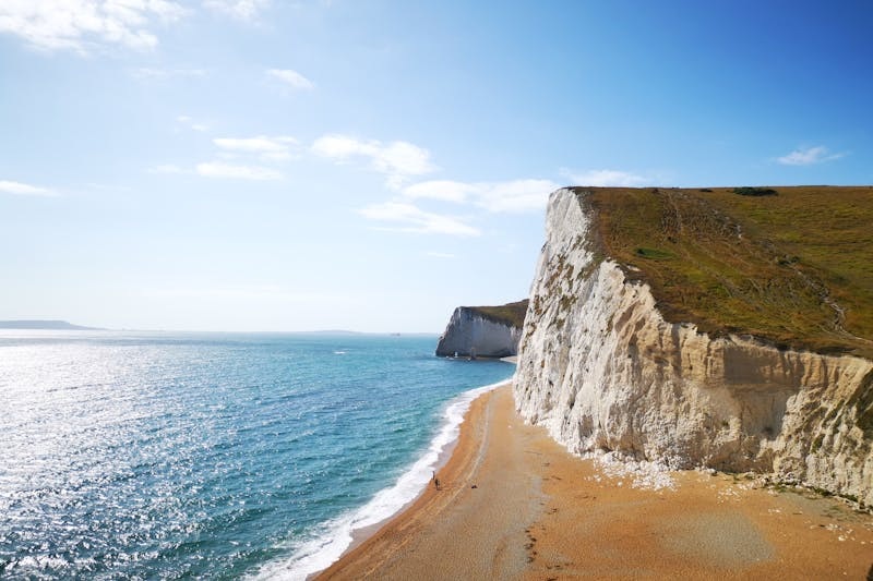 Cliffs and blue sea along the Isle of Wight coastline on a sunny day.