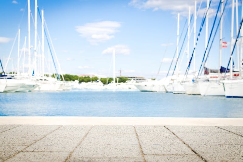 View of a marina from the ground with boats docked in the distance.
