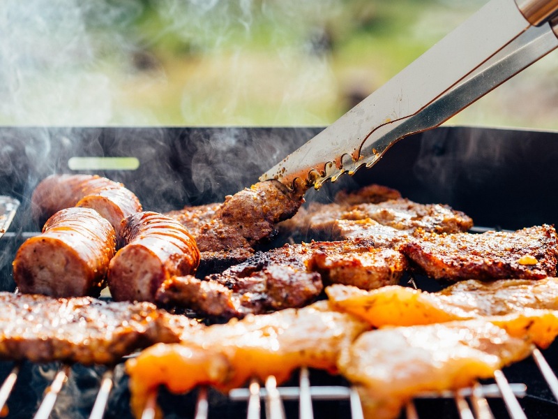 Close-up of meat grilling over flames on a barbecue.