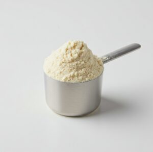 Scoop of white powdered nutritional supplement in a measuring spoon.